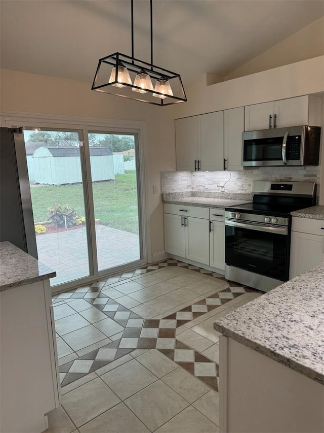 kitchen with white cabinetry, lofted ceiling, decorative light fixtures, light tile patterned floors, and appliances with stainless steel finishes