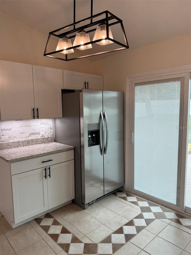 kitchen with pendant lighting, white cabinets, stainless steel refrigerator with ice dispenser, light tile patterned floors, and light stone counters