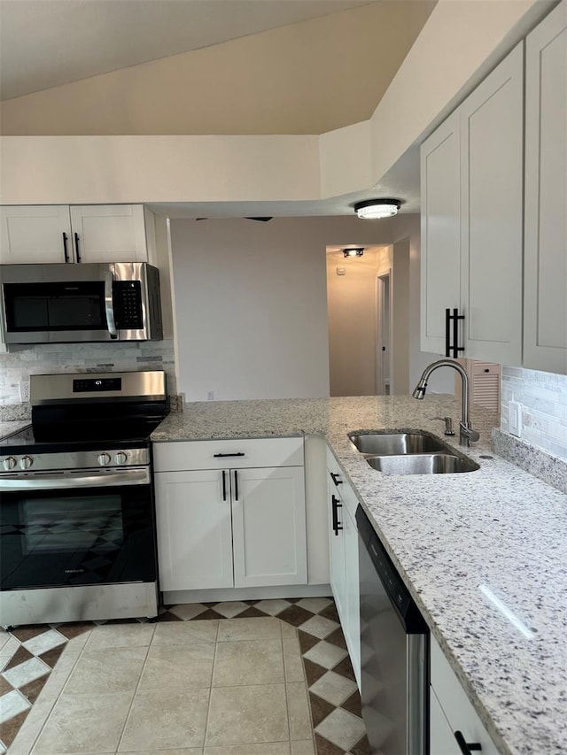 kitchen featuring white cabinetry, sink, vaulted ceiling, and appliances with stainless steel finishes