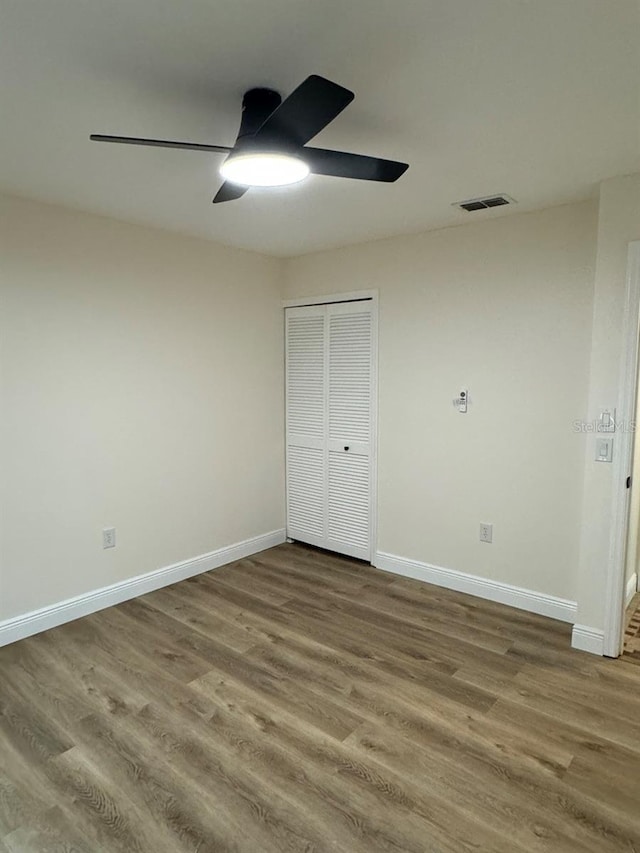 unfurnished bedroom with a closet, hardwood / wood-style flooring, and ceiling fan