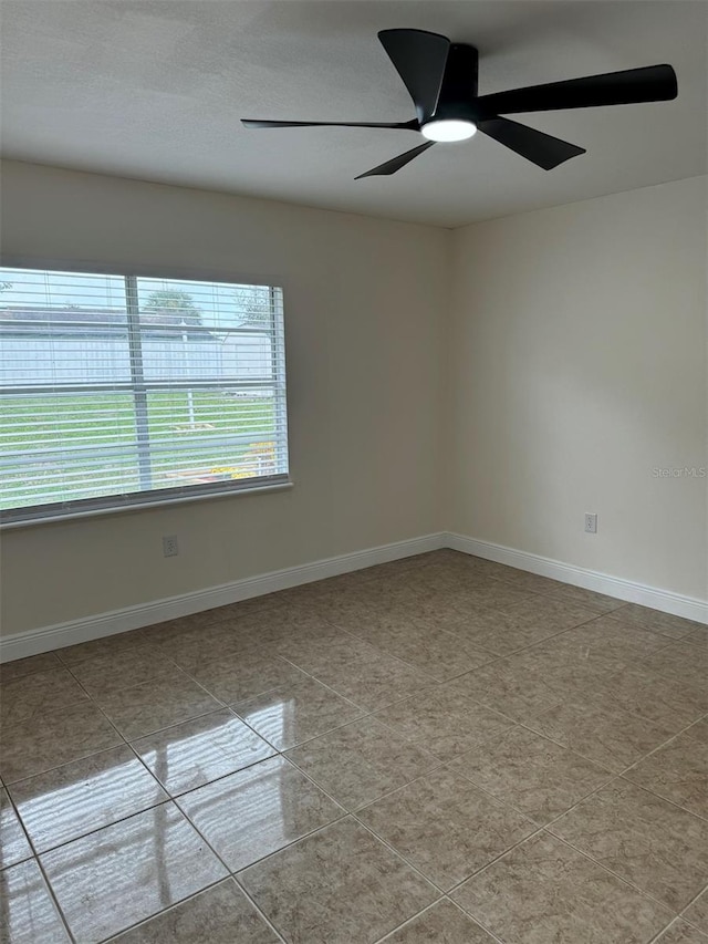 spare room with ceiling fan and light tile patterned floors