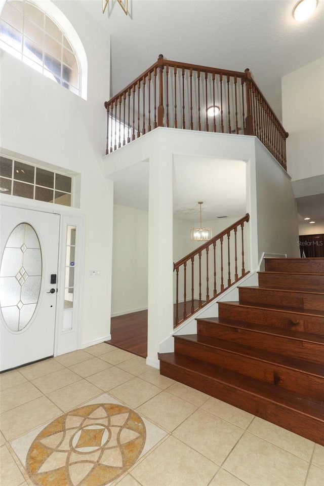 entrance foyer featuring tile patterned floors, a high ceiling, and an inviting chandelier