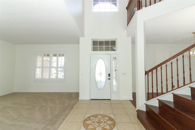 entryway with light tile patterned floors, a towering ceiling, and a textured ceiling