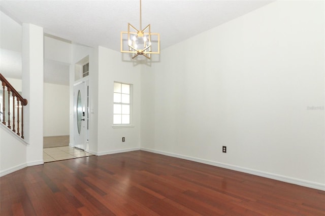 empty room featuring hardwood / wood-style flooring and a notable chandelier