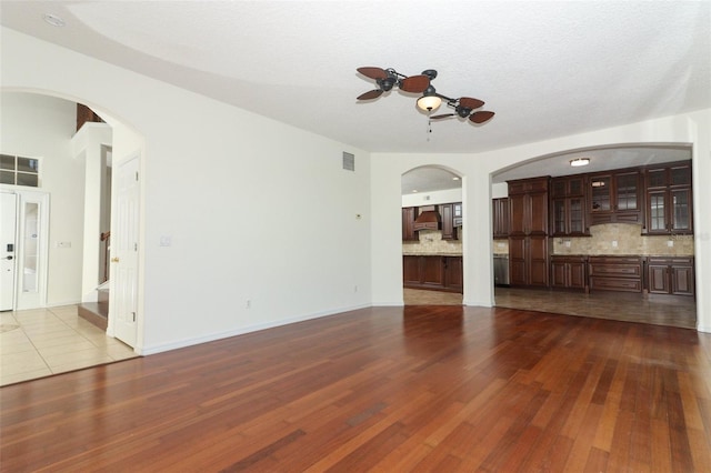 unfurnished living room with ceiling fan, a textured ceiling, and hardwood / wood-style flooring