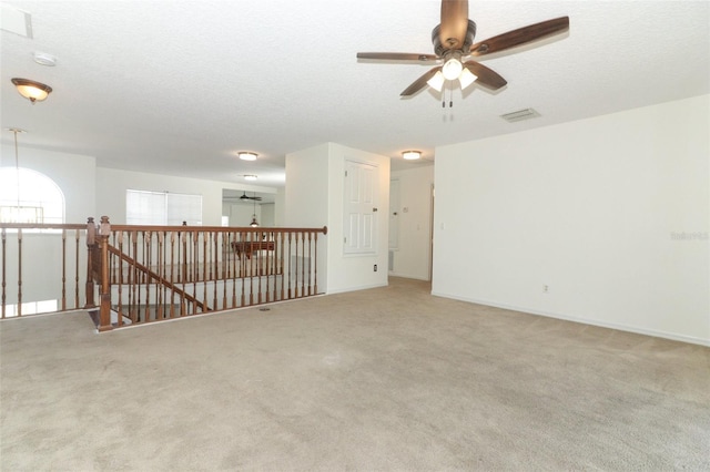 carpeted empty room with ceiling fan and a textured ceiling