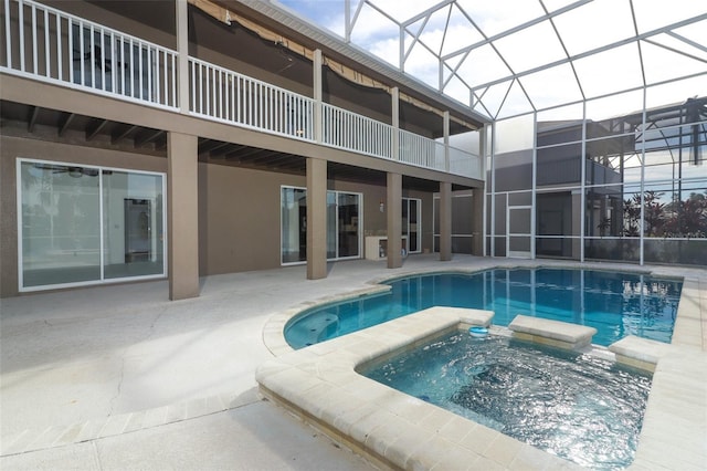 view of pool with glass enclosure, a patio area, and an in ground hot tub