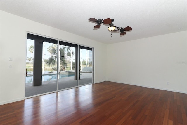 spare room featuring ceiling fan, dark wood-type flooring, and a textured ceiling