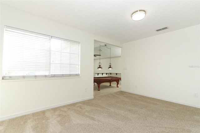 unfurnished room featuring pool table, a textured ceiling, and carpet flooring