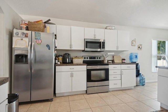 kitchen with light tile patterned flooring, appliances with stainless steel finishes, and white cabinetry