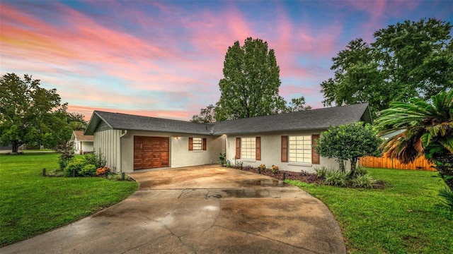 ranch-style home featuring a garage and a lawn