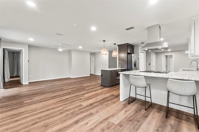 kitchen featuring sink, ceiling fan, hanging light fixtures, stainless steel fridge with ice dispenser, and light hardwood / wood-style floors