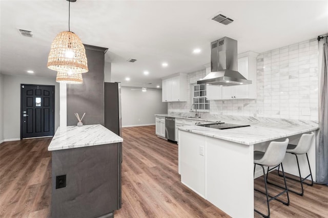 kitchen with white cabinetry, decorative light fixtures, dark hardwood / wood-style floors, appliances with stainless steel finishes, and wall chimney range hood