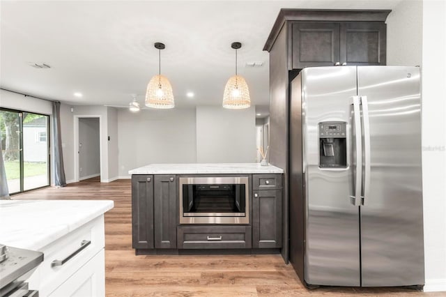 kitchen with dark brown cabinets, stainless steel fridge, white cabinetry, and decorative light fixtures