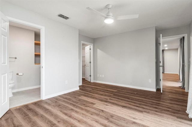 unfurnished bedroom with hardwood / wood-style floors, ceiling fan, and ensuite bath