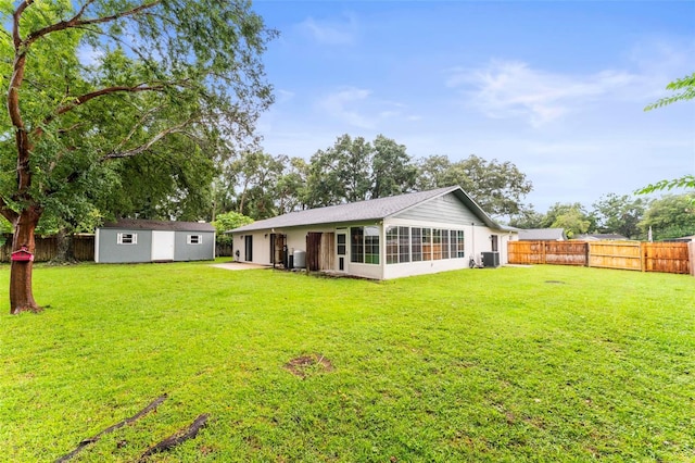 back of property featuring cooling unit, a lawn, and a storage shed