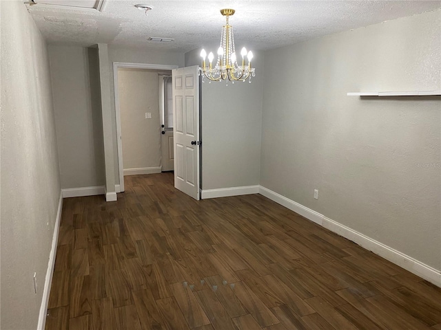 unfurnished room featuring dark hardwood / wood-style floors, a chandelier, and a textured ceiling