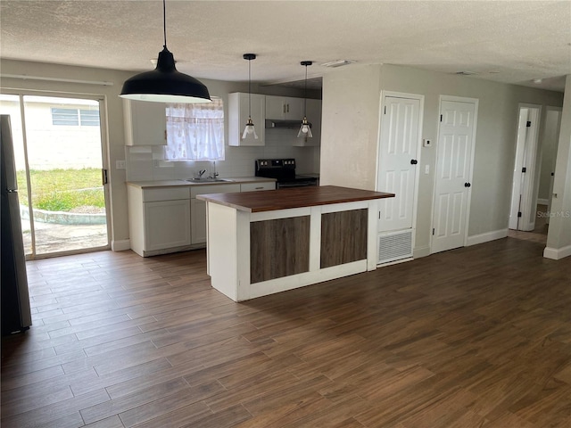 kitchen with dark wood-type flooring, butcher block counters, sink, hanging light fixtures, and black range with electric stovetop