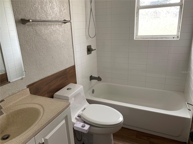 full bathroom featuring vanity, tiled shower / bath, wood-type flooring, and toilet