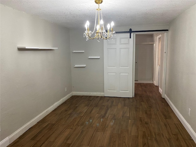 unfurnished dining area with dark wood-type flooring, a barn door, a textured ceiling, and a notable chandelier