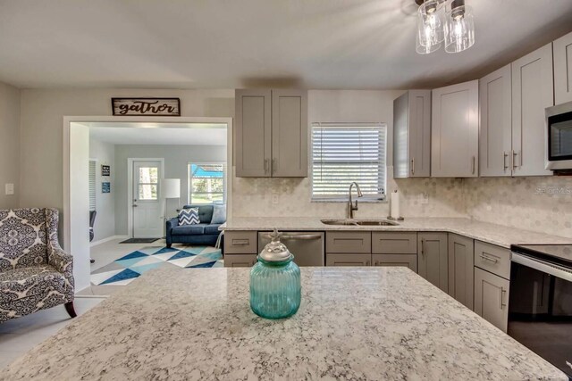 kitchen with appliances with stainless steel finishes, a wealth of natural light, gray cabinetry, and sink