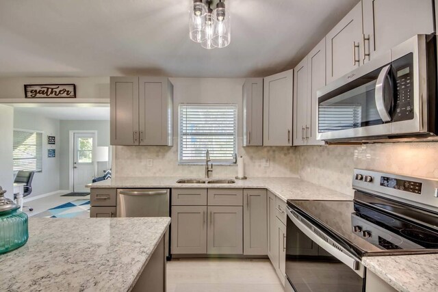 kitchen featuring stainless steel appliances, sink, backsplash, and a chandelier