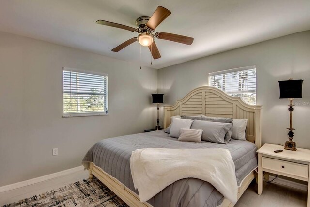 bedroom with multiple windows, ceiling fan, and hardwood / wood-style floors