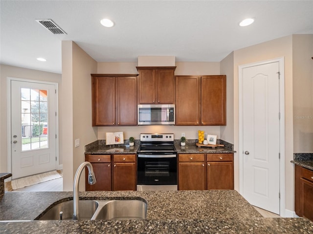 kitchen with sink, dark stone counters, and appliances with stainless steel finishes