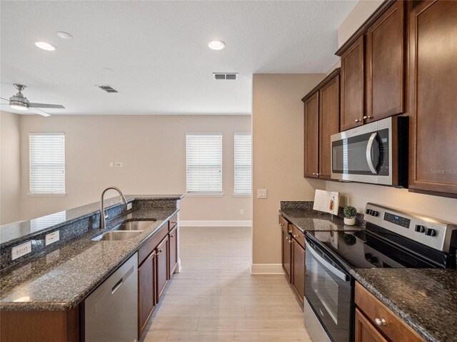 kitchen featuring a wealth of natural light, sink, appliances with stainless steel finishes, and dark stone counters