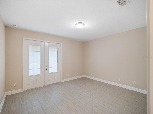 spare room featuring light hardwood / wood-style flooring and french doors