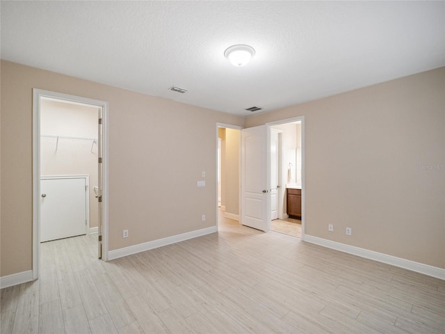 unfurnished room featuring light hardwood / wood-style flooring and a textured ceiling