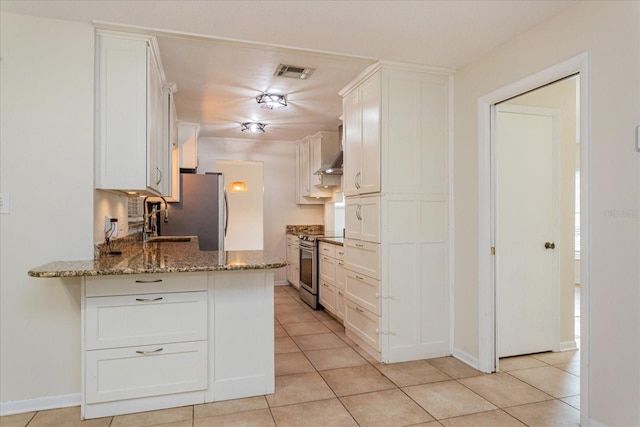 kitchen featuring appliances with stainless steel finishes, white cabinetry, kitchen peninsula, light tile patterned floors, and stone counters