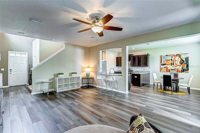 living room featuring ceiling fan, a textured ceiling, sink, and wood-type flooring