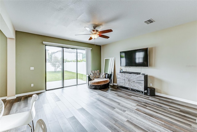 sitting room featuring light wood-type flooring, ceiling fan, and a textured ceiling