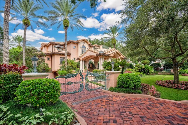 mediterranean / spanish-style home featuring a tile roof, a gate, fence, and stucco siding