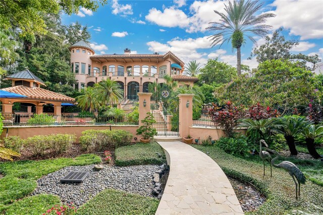 view of front facade with a fenced front yard, a chimney, a gazebo, a gate, and a balcony