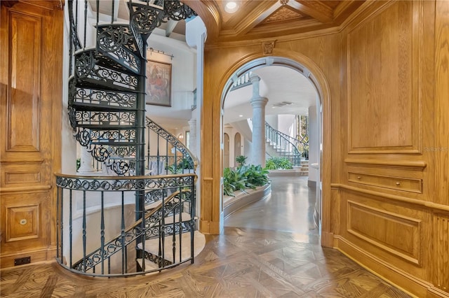 hall with decorative columns, arched walkways, coffered ceiling, stairs, and crown molding