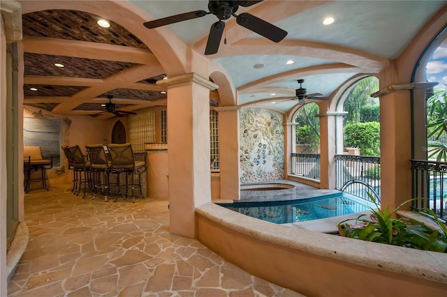 view of pool with arched walkways, a jacuzzi, and ornate columns