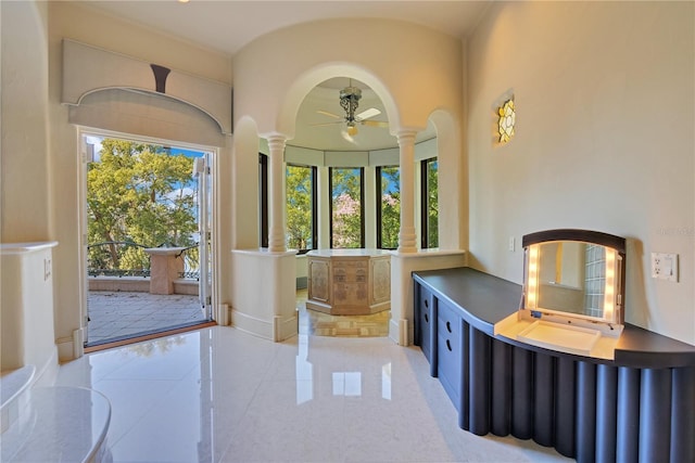 foyer with arched walkways, decorative columns, light tile patterned floors, a ceiling fan, and baseboards