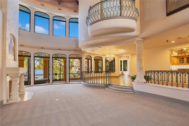 interior space with a chandelier, a towering ceiling, decorative columns, and baseboards