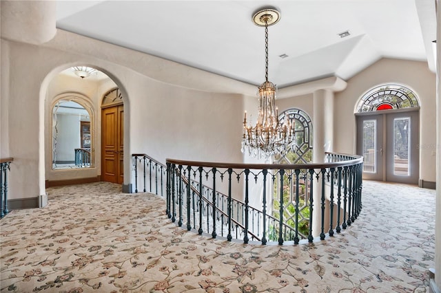 corridor featuring carpet floors, visible vents, an upstairs landing, and an inviting chandelier