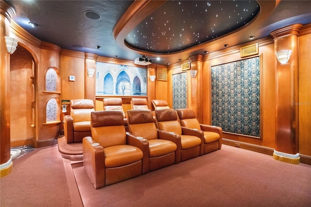 cinema room featuring carpet floors, arched walkways, crown molding, and a tray ceiling