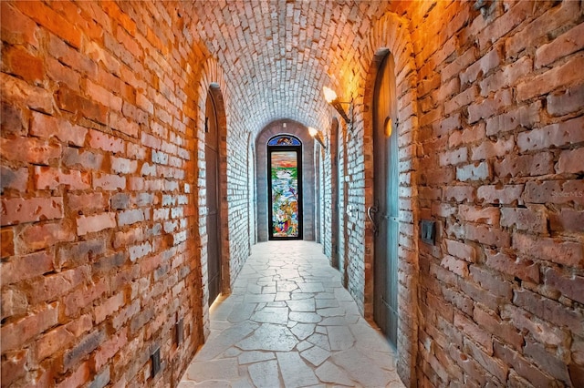 corridor featuring brick ceiling, brick wall, and stone tile flooring