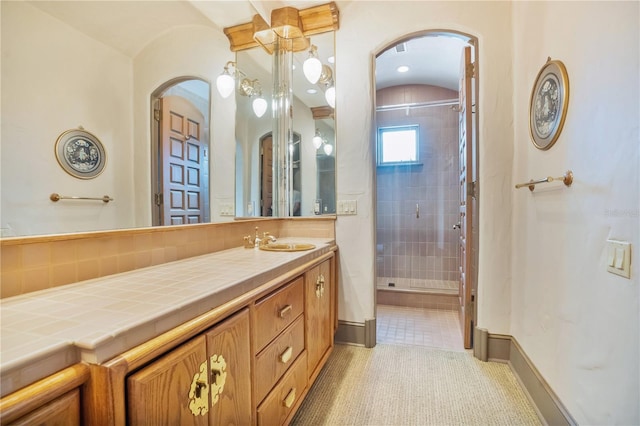 bathroom with a stall shower, vanity, baseboards, and tile patterned floors