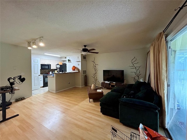 living room featuring track lighting, a textured ceiling, ceiling fan, and light hardwood / wood-style floors