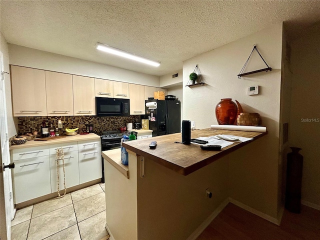 kitchen with light tile patterned floors, black appliances, kitchen peninsula, decorative backsplash, and a textured ceiling