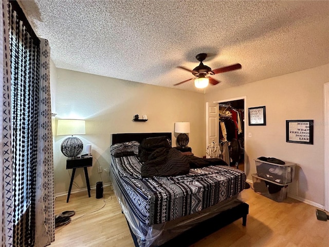 bedroom featuring a closet, ceiling fan, light hardwood / wood-style floors, and a textured ceiling