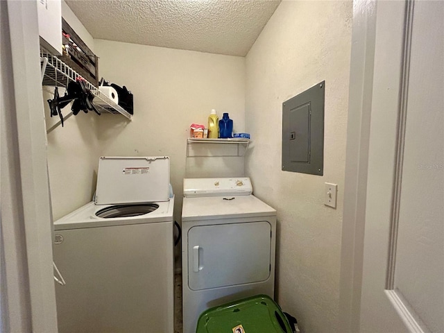 laundry room featuring a textured ceiling, electric panel, and washer and clothes dryer