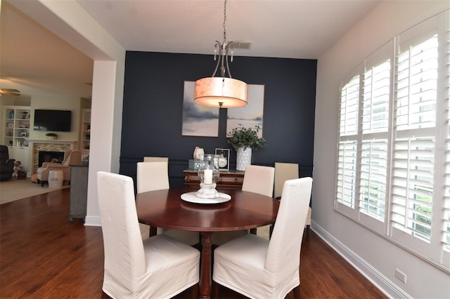 dining area featuring dark wood-type flooring and a fireplace