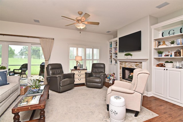 living room featuring hardwood / wood-style floors, ceiling fan, and a tile fireplace